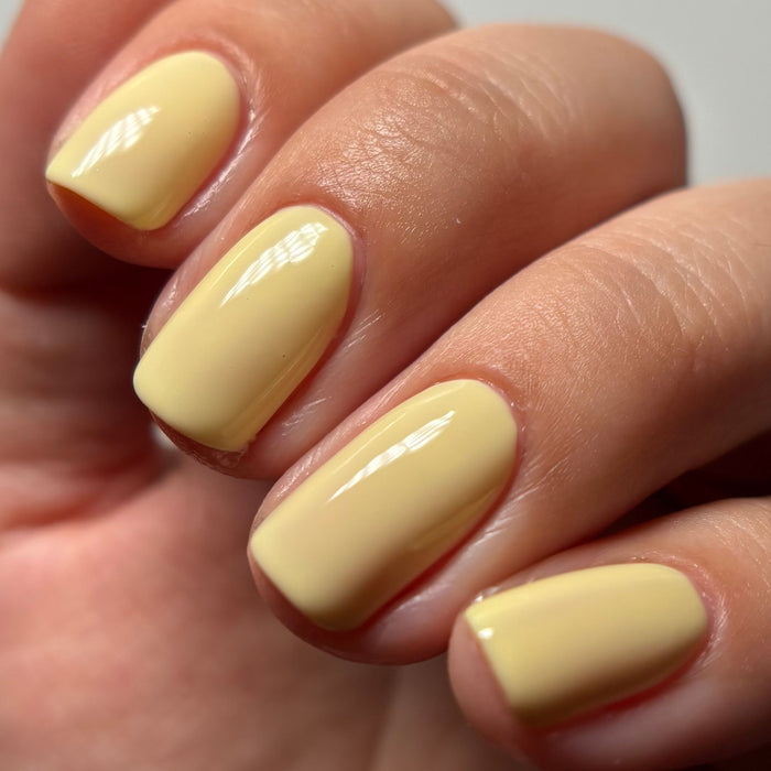 A close-up of four fingernails painted with LONDONTOWN’s Banana Pudding—a glossy, pastel yellow nail polish—captures a mellow yellow vibe reminiscent of a sheer lipstick or subtle yellow lip color.
