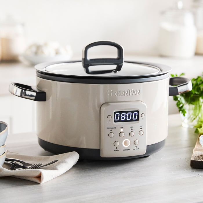 Macadamia-colored 4-quart slow cooker on a counter next to bowls and a folded napkin.