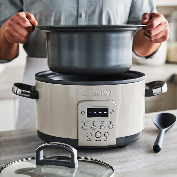Person lifting pot from a Macadamia-colored 4-quart slow cooker on a kitchen counter.