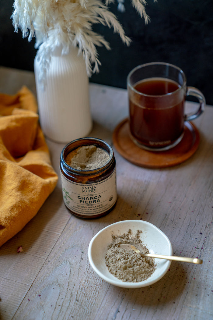 Jar of Chana Masala Powder on a table with a cup of tea and a bowl of powder.
