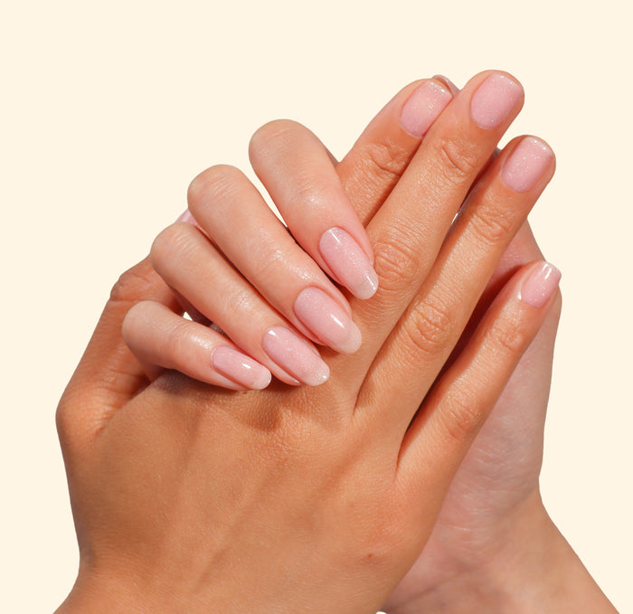 Two hands with neatly manicured nails painted in LONDONTOWN’s Confetti Cake are shown against a light, neutral background.