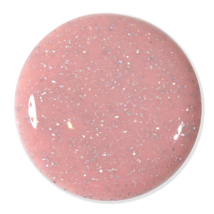 A round swatch of LONDONTOWN’s Confetti Cake nail polish—a sweet pastel pink shade with fine silver confetti sparkle and a glossy finish—is shown against a white background.
