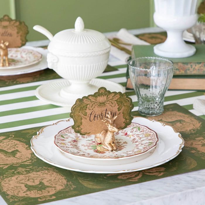 An elegant table setting with the Deer Place Card Holder holding the Moss Fable Toile Place Card with the name "Courtney" written in cursive, and the Moss Fable Toile Placemat underneath.