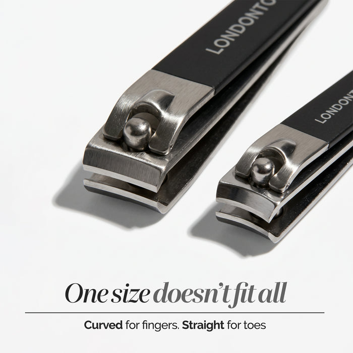 The LONDONTOWN Nail Clipper Duo Set - Black features two metal clippers in differing sizes, neatly placed side by side on a white background. Text highlights their intended uses—one sized for fingernails and the other for toenails—while both promise a clean cut for precise grooming.