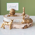 An Owl, Rabbit, Fox and Deer place card holder stacked on cylinders of wood with the Dark Green Frame Place Card with "Sarah" written on it in cursive, being held up by a slot in the owl's back.