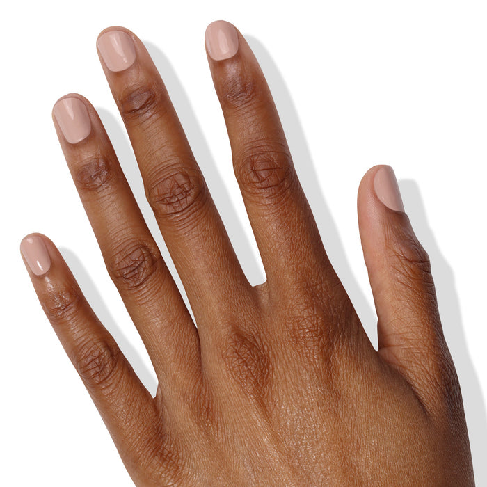 A hand with medium brown skin showing visible veins, four fingers extended, and nails painted in the creamy pale pink shade Pampas Beige by LONDONTOWN.