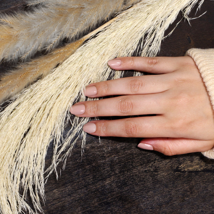 A close-up of a hand with LONDONTOWN's Pampas Beige nails resting on a surface adorned with delicate dried grasses.