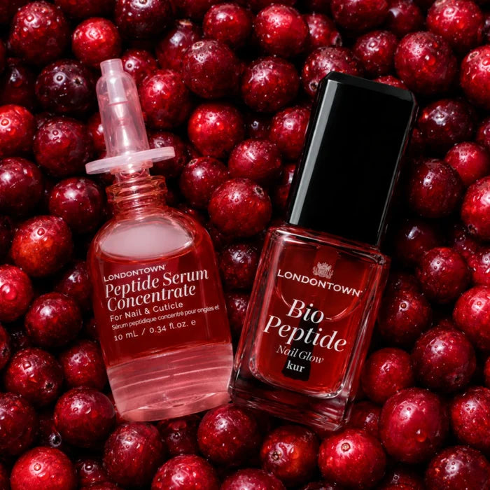 Two bottles of award-winning LONDONTOWN Peptide Gloss Duo resting on a bed of fresh red cranberries.