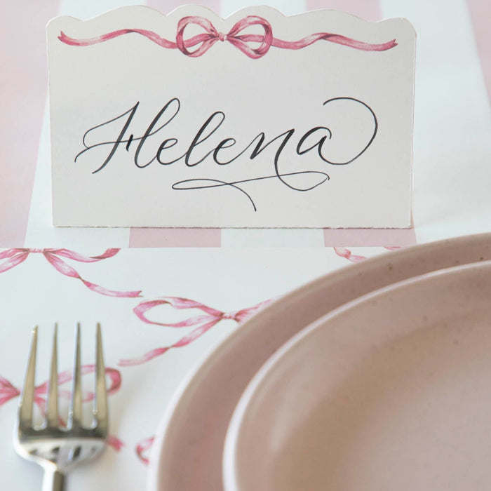 A Hester & Cook Pink Bow Place Card is placed on a table, adding loveliness to the setting.