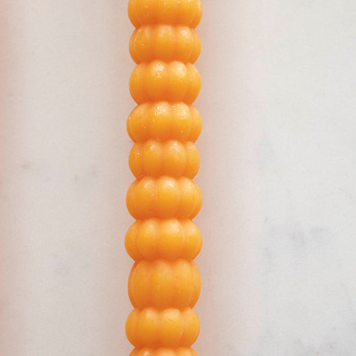 Close-up of the orange pumpkin taper candle.