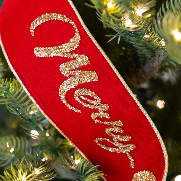 Red ribbon with gold 'Merry' text on a Christmas tree.