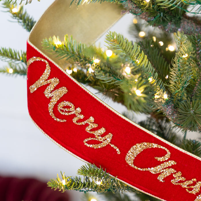 Red 'Merry Christmas' ribbon with gold text on a Christmas tree.