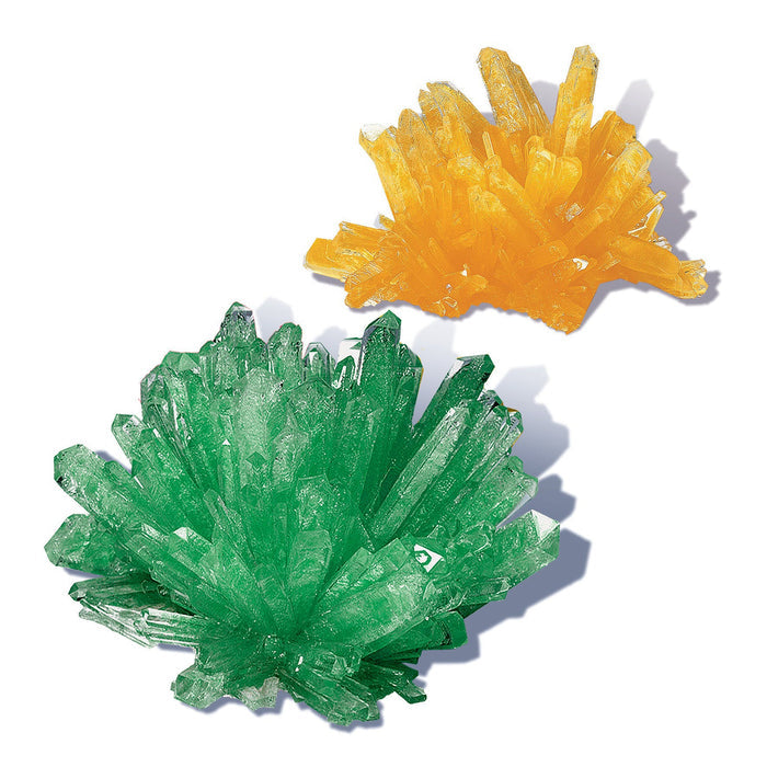 Two clusters of sharp, pointed crystals—one green, one yellow—radiate outward, created with the Smithsonian Crystal Growing Value Set by Smithsonian, displayed against a white background.