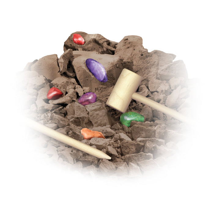 The Smithsonian Rock And Gem Value Set by Smithsonian features brown clay rubble embedded with colorful gems—red, purple, orange, and green. Wooden digging tools, mallet, and chisel are included for interactive STEM exploration.
