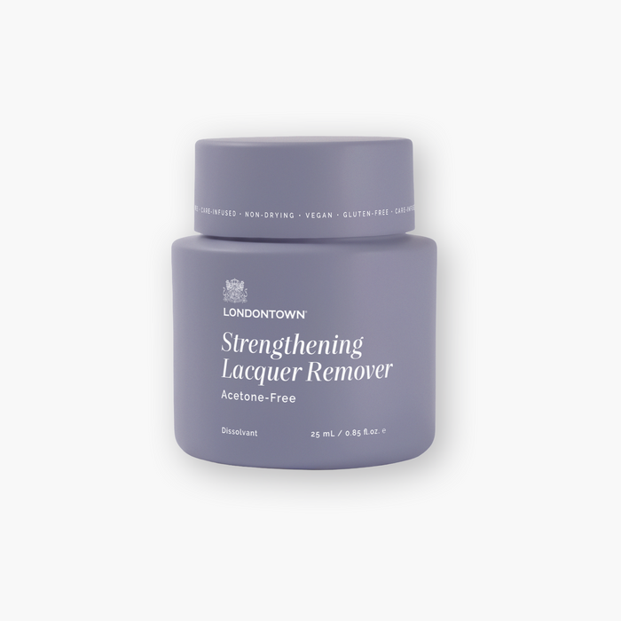 A purple container of LONDONTOWN Strengthening Lacquer Remover Pot, labeled as acetone-free, vegan, gluten-free, and containing 25 mL (0.85 fl. oz.), is perfect for a fresh start with quick cleaning—just dip, twist, and reveal beautifully clean nails in seconds.