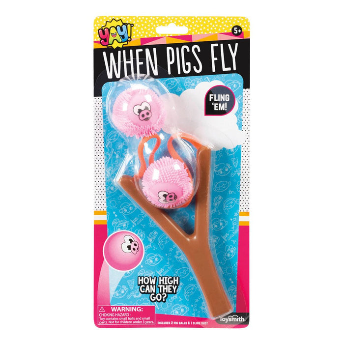 The YAY! When Pigs Fly toy by YAY! features two pink flying pig balls and a brown tree-shaped slingshot in humorous packaging with “Fling Em!” and “How high can they go?” plus a warning label at the bottom.